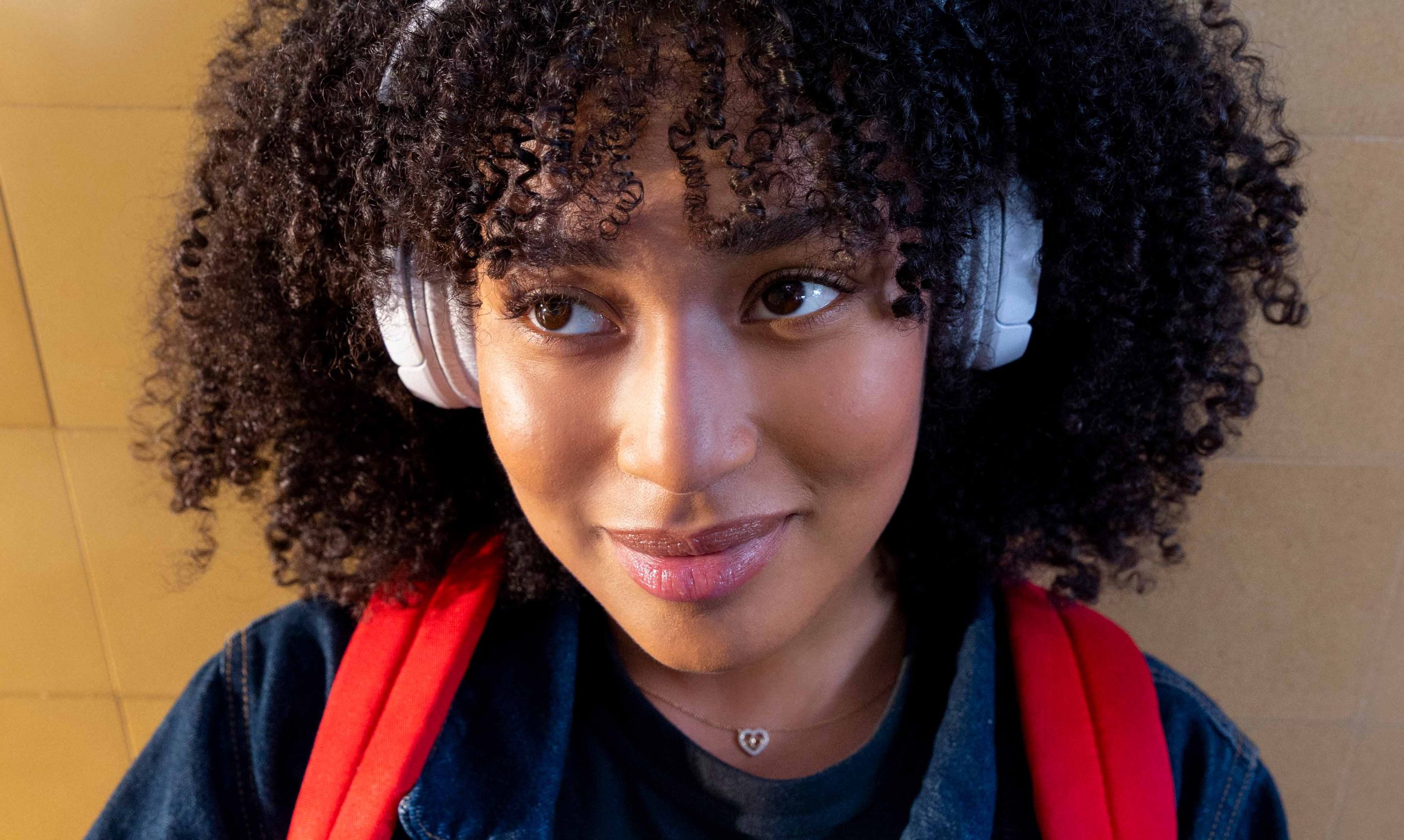 Foto van vrouw met hoofdtelefoon op, ze glimlacht erbij.